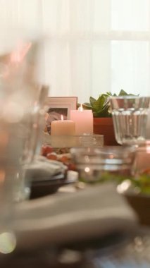 Cam eşyalar, yeşillik ve şenlik için hazırlanmış yemek masasının dikey yakın çekimi.