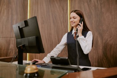 Otel müşterileri ve oda rezervasyoncuları ile çekici genç resepsiyonist iletişimi medyum yakın çekim