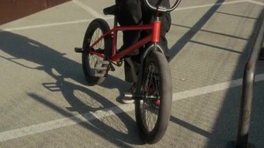 Güneşli yaz gününde kaykay parkında bisikletli BMX sürücüsünün yakın çekim görüntüleri.