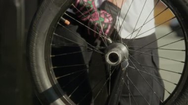 BMX sürücüsünün eldivenli görüntüsünü yakın çekimde bisiklet tekerleğinin mandalını sıkılaştırmak için ingiliz anahtarı kullanarak açık havada bakım yaparken