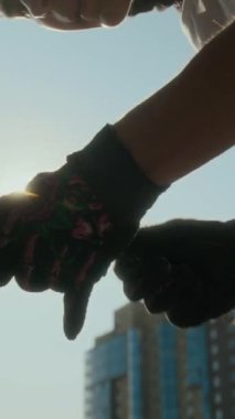 BMX sürücünün eldivenli dikey yakın çekimi dışarıda bisiklet tekerleğini tamir etmek için altıgen anahtarla kameraya parlayan güneş ışığıyla.