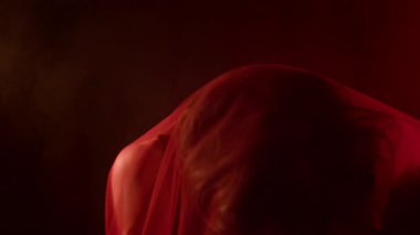 Melankolik Z neslinin kırmızı peçeyle örtülü yakın plan görüntüsü. Vücut hatları belirginleşiyor ve gizem hissi uyandırıyor.