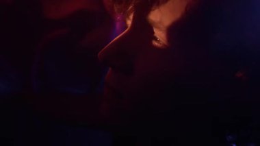 Kafkasyalı kıvırcık saçlı adamın kafasını ve ellerini örten kırmızı peçeden kurtulmaya çalışırkenki aşırı yakın çekimi.