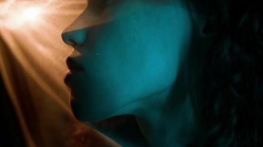 Gözü kapalı, loş bir odada şeffaf beyaz kumaşın altında saklanan Kafkas bir kızın aşırı yakın çekimi.