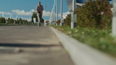 Parlak güneşli bir günde Downton 'da kaldırımlı yolda elektrikli scooter kullanan sakallı bir adamın düşük açılı çekimi.