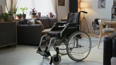 Oturma odasında rahat bir masa ve arka planda kanepe olan siyah tekerlekli sandalye.