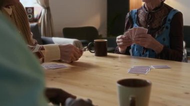 Oturma odasında oyun oynamadan önce ahşap masada oturup kartlarını alan yaşlıları yakından izleyin.