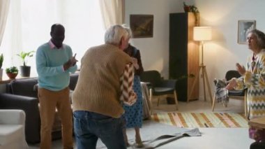 Huzurevindeki partinin tadını çıkarırken enerjik bir şekilde dans eden ve gülümseyen yaşlı arkadaşlar.