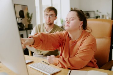 Ofiste birlikte çalışırken bilgisayar ekranındaki kodları kontrol eden iki yorgun iş arkadaşının medyum görüntüsü.