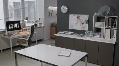 Masasında röntgen resimleri olan modern veterinerlik bürosunun içinde, tıbbi malzemelerle dolu raflar, ilan panosu ve masanın üzerinde tıbbi form olan pano.