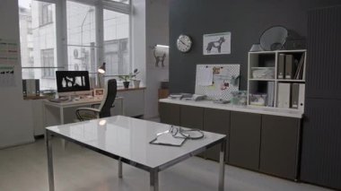 Masasında steteskop ve pano olan veteriner kliniğinin içi duvarlarda evcil hayvan anatomisi posterleri, raflar ve röntgen görüntülerini gösteren bilgisayar.