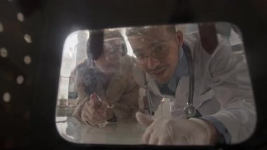 Veteriner ve müşterinin klinikteki evcil hayvan taşıyıcısının açık penceresinden hayvanı gözlemleyip teşhis ve tedavi seçeneklerini tartışırken POV görüntüsü