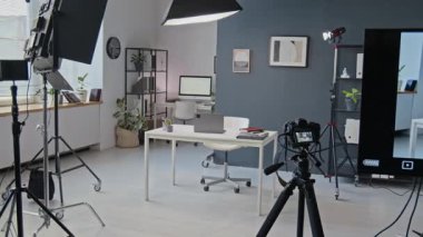 Beyaz masalı, sandalyeli ve dekorlu raflı modern, iyi ışıklandırılmış ofis alanının video çekimleri için stüdyo kurulumu yok.