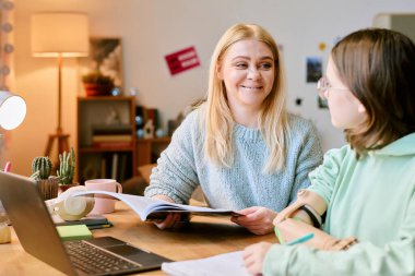 Protez kollu bir anne ve kızı rahat bir ofiste çalışma projesini tartışıyorlar.