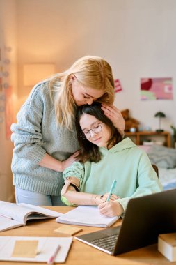Anne, masa başında çalışırken kızının üzerine protez elle eğiliyor. Yakınlarda bir yerde kitap ve dizüstü bilgisayar bulundurarak onu cesaretlendiriyor.