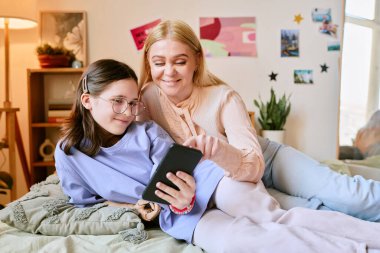 Anne sıcacık gülümserken protez elli kız gözlüklü kız, arka planda hoş dekorasyonlarla birlikte ekrana bakıyor ve neşeli anları paylaşıyor.