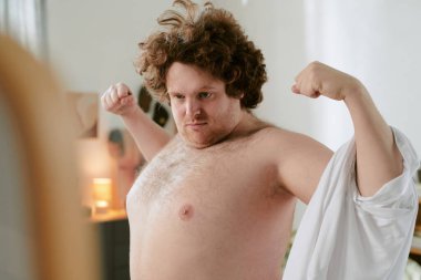 Evde kendinden emin bir şekilde el kol hareketi yapan, rahat bir tavır sergileyen üstsüz bir adamın portresi. Onun ifadesi gelişigüzel bir ortamda kararlılık ve umursamazlık karışımı taşıyor.