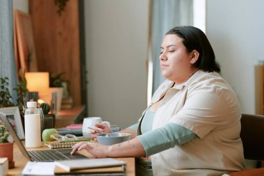 Merkez büroda organize masalarda çalışırken kameraya bakan kadının portresi konsantrasyonunu ve uzmanlığını ön plana çıkarıyor.