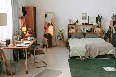 Rahat, modern yatak odası, düzenli bir masa alanı rafları, rahat bir yatak ve hareketli bir yaşam alanı yaratan dekoratif unsurlar.