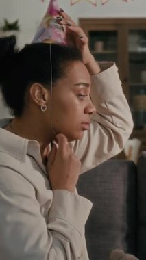 Genç bir kadının kendine ve kızına parti şapkası takıp oturma odasında pelüş oyuncaklarla oynaması dikey bir bakış açısı.