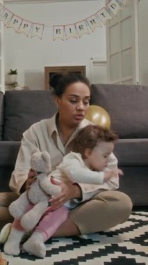 Anne 'nin yorgun küçük kızıyla oynamaya çalışması ve oturma odasında vakit geçirirken oyuncaklarını sunması dikey bir bakış açısı.