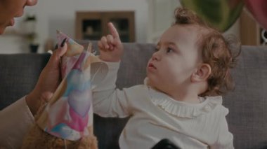 Küçük kız oyuncak ayının şapkasını çıkarıp kafasına geçirip genç annesiyle selfie çektirmeye çalışıyor.