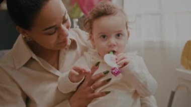 Küçük kızın kameraya baktığı yakın plan görüntüler, sonra anne kucağına bebeği alıp ağzına parti düdüğü koyuyor.