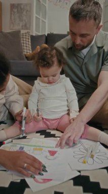 Küçük kızıyla konuşan çok ırklı eşlere dikey bir bakış açısı ve birlikte halıda otururken onun renkli çizimlerini keçeli kalemle izlemek