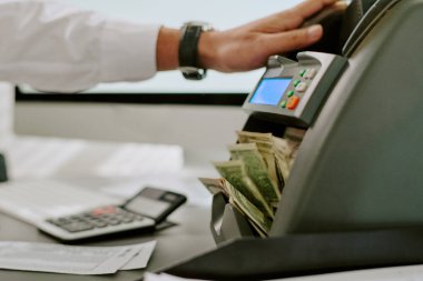 Elektronik kasayı hesap makinesi ve nakit para ile ayarlayan, iş ortamını yansıtan, modern işyerindeki mali işlem sürecini resmeden kişiye yakın çekim