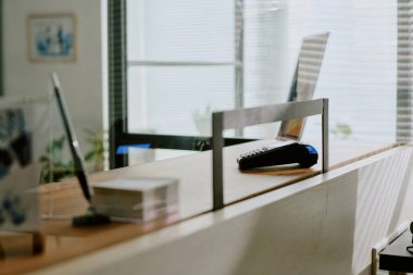 Çalışma alanını aydınlatan geniş ofis penceresinden güneş ışığı yayılıyor. Çeşitli ofis malzemeleri ve huzurlu bir ortamda masanın üzerinde dinlenen bir dizüstü bilgisayar.