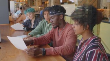 Kafede sipariş vermeye hazırlanırken çeşitli kız arkadaşlarla menüyü tartışan Afro-Amerikan gencin cam penceresinden bakın