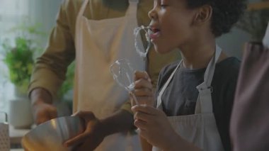 Küçük Afrikalı Amerikalı çocuk çırpılmış yumurta beyazı ile kaplanmış çırpı çırpıyor.