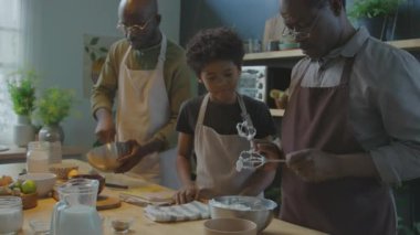 Afrika kökenli Amerikalı büyükbaba, torununa çırpılmış yumurta beyazı çırpılmış çırpılmış çırpı veriyor. Çocuk, ailesiyle evde yemek pişirirken onları yalıyor.