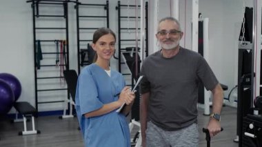 Medikal üniformalı neşeli genç kadın doktor portresi ve spor kıyafetleri giymiş, elinde baston tutan ve spor salonunda kameraya bakan olgun bir adam.