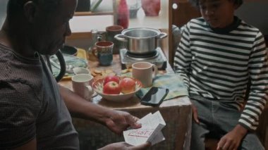 Fakir bir aileden gelen Afrikalı Amerikalı çocuk babasının gecikmiş faturaları dinleyerek küçük bir mutfakta oturuyor.