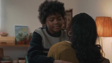 Afrika kökenli, kıvırcık saçlı, tanınmayan annesine sarılan genç bir çocuğun yavaş çekim portresi.