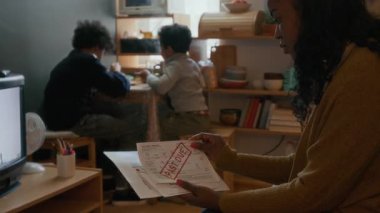 İki Afro-Amerikalı çocuk masada birlikte yemek yerken anneleri de vadesi geçmiş faturalar için strese giriyor.