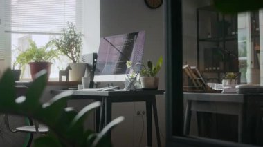 Ekranda bilgisayar kodları, saksı bitkileri ve rahat ofiste minimalist dekoru olan modern işyeri