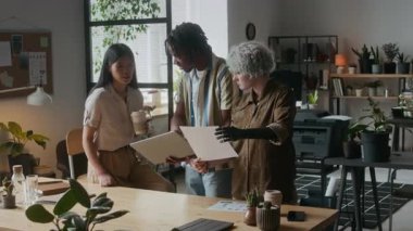 Çeşitli iş adamları fikirleri tartışıyor, belgeleri inceliyor ve modern rahat ofiste iş günlerinde dizüstü bilgisayarda proje hazırlıyorlar.