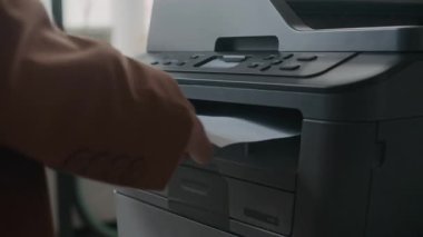 İş günlerinde ofisteki yazıcıdan taranan belgeleri alan tanınmayan bir iş kadınının yakın çekim görüntüleri.