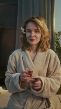 Kafkasyalı mutlu bir kadının masaj seansından sonra kaftan giyip içki içtiği dikey portre fotoğrafı.