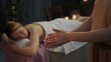 Masajdan önce avuçlarına yağ sürerken, masaj masasında uzanırken, tanınmayan bir masözün yavaş çekimleri.