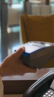 Oteldeki resepsiyonist tarafından tutulan kredi kartından kredi kartı alan tanınmayan bir adamın dikey yakın çekimi.