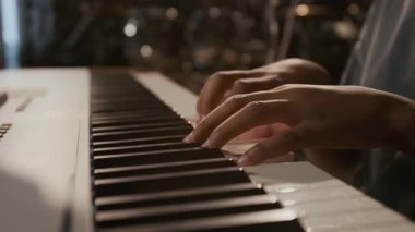 Müzik stüdyosundaki provalar sırasında dijital klavye çalan tanınmayan ergen çocuğun ellerine yakından bakın.