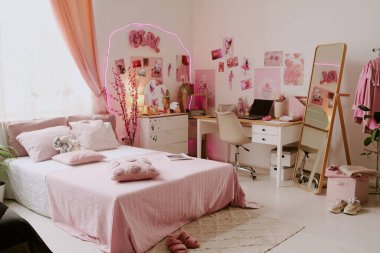 Geniş yatak odası, pembe posterlerle süslenmiş oda, neon lambaları ve ahşap mobilyalar.