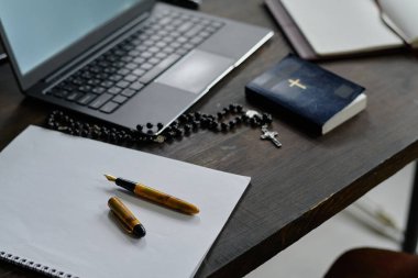 Kalem, dizüstü bilgisayar, İncil ve tespih ile açılmış defter rahibe odasındaki masanın üzerinde duruyor.