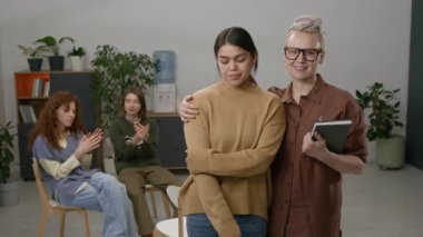 Kamera önünde kucaklaşan ve gülümseyen iki kadının portre çekimi, grup terapisi sırasında konuşan iki kadın.