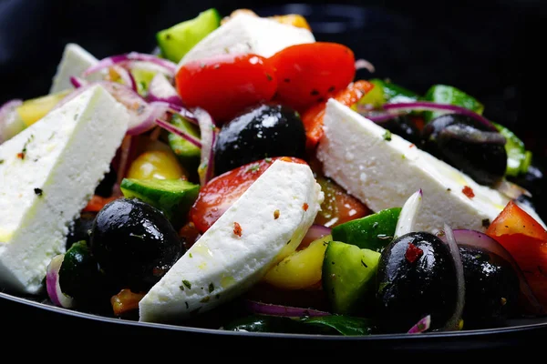 Greek salad on a black background. Homemade food. Food in a restaurant.
