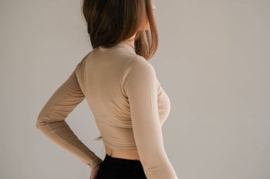 Arka cebinde bir elle bej rengi uzun kollu bluzuyla arka koltukta duran güzel genç bir kadın. Çeşitli temel giysiler giyen bir kadın. Model yap. Fikirleri kabul et. Giysileri kapatın. Asgari düzeyde. Basitlik.