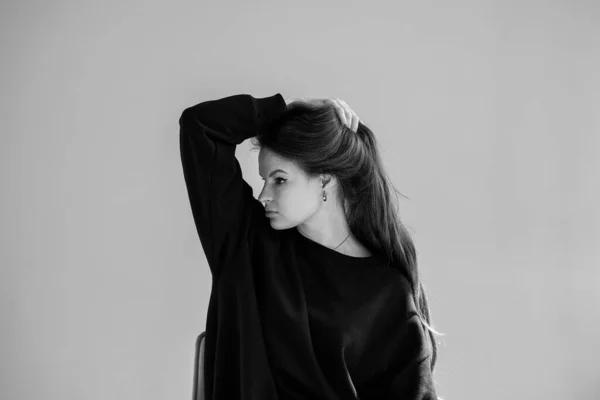 Vrouw Zwart Sweatshirt Houdt Haar Lange Haar Bij Hand Kijkt — Stockfoto